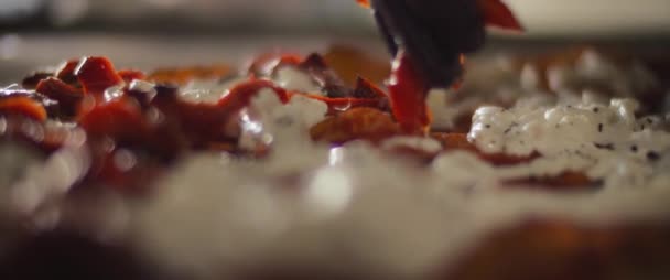 Chef verspreidt rode paprika 's over een kant en klare burrata al taglio pizza. Close up, slow motion — Stockvideo