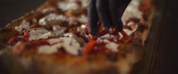 Chef verspreidt rode paprika 's over een kant en klare burrata al taglio pizza. Close up, slow motion — Stockvideo