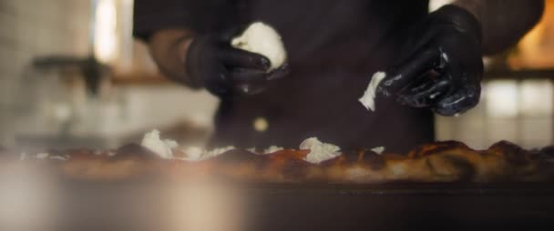 Großaufnahme eines Kochs, der Burrata-Käse auf einer traditionellen Taglio-Pizza verteilt. — Stockvideo