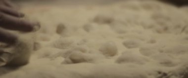 Şef elleriyle geleneksel pizza hamuru hazırlıyor, yavaşça hamur yoğuruyor. Yaklaşın, ağır çekim.