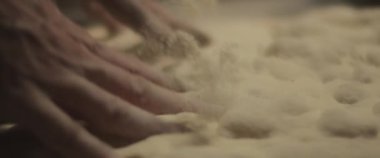 Şef elleriyle geleneksel pizza hamuru hazırlıyor, yavaşça hamur yoğuruyor. Yaklaşın, ağır çekim.
