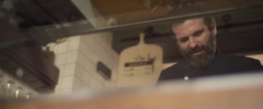 Restoranın mutfağında çalışan sakallı bir İspanyol şef. Yavaş çekim, orta çekim..