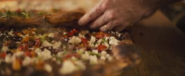 Farklı malzemelerle lezzetli al taglio pizzaları bir pizza kafede ahşap bir yüzeye yerleştiriliyor. Yavaş çekim