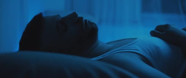 ベッドの上に寝そべっている大人の兵士の近くで 外傷後の対処 うつ病 精神衛生の概念 リアルタイム ハンドヘルド 青の照明 — ストック動画