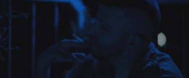 Sigara içen yetişkin bir asker, geceleri bunalım ve bunalımla boğuşuyor. Travma sonrası stres bozukluğu, depresyon, akıl sağlığı konsepti. Yaklaş, yavaş çekim, mavi ışık.