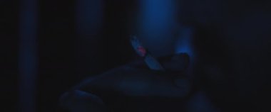 Geceleri sigara içen bir adamın anksiyete ve travma sonrası durumuyla ilgilenirken fotoğrafını çek. Travma sonrası stres bozukluğu, depresyon, akıl sağlığı konsepti. Yaklaş, yavaş çekim, mavi ışık.