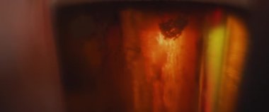 Bir bardak biranın içinde köpüklü köpükler, makro. Kırmızı arkaplan ile kapatın. Soyut görünüm