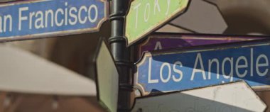 Dünyanın farklı şehirlerine, San Francisco, Tokyo, LA, Madrid 'e giden yolu gösteren turistik bir tabela. Ağır çekim, yakın çekim..