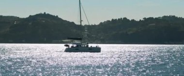 Bir yaz günü kırsal tepe kıyısında yelken açan bir yat. Yavaş çekim.