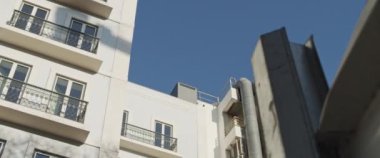 Güneşli bir günde beyaza boyanmış eski bir Avrupa tarzı konut binasının cephesi. Yavaş çekim.