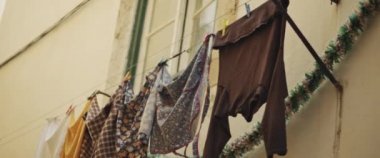 Çamaşırları yıkayıp, kuruması için apartmanın dışında tipik bir Avrupa şehir sokağında iple asılmış. Ağır çekim, yakın çekim..
