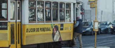 Lizbon, Portekiz - 07 Aralık 2019: Geleneksel sarı tramvaya giren bir adam.