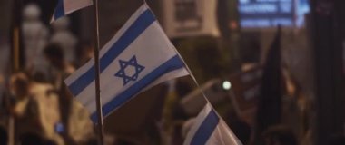 Israeli flags waving during protests against the government at night. Slow motion.