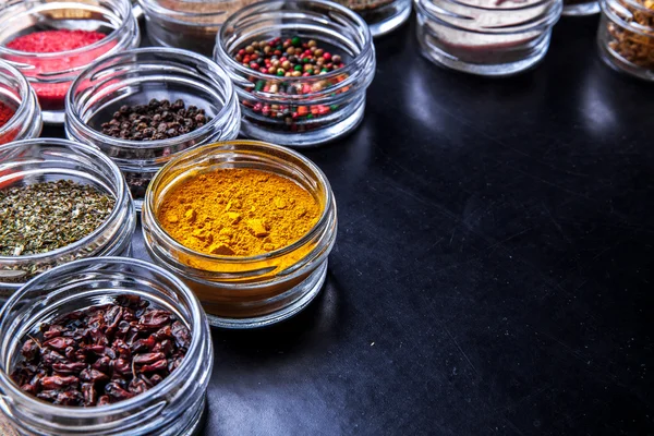 Spices on black background in special jars. Food — Stock Photo, Image