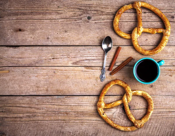 Leckeres Frühstück, eine Brezel mit Kaffee auf Holzuntergrund. — Stockfoto