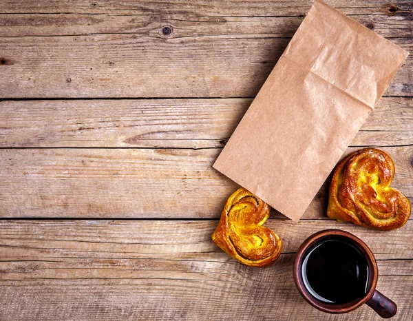 Pâtisseries maison. coeur de chignon dans un sac en papier. pour le petit déjeuner avec café. Matin, boissons, nourriture — Photo