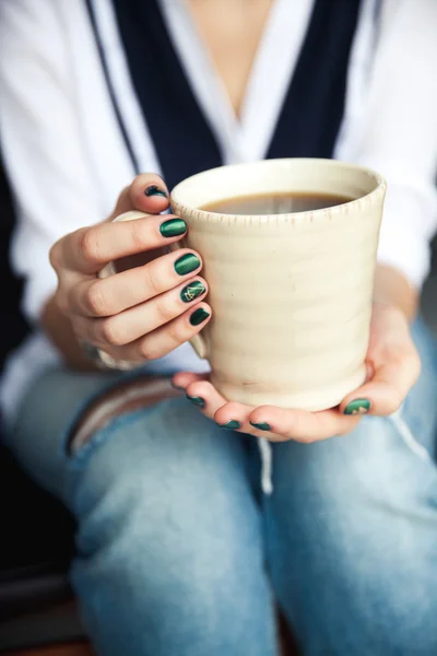Stilvolles modisches Mädchen mit einer Tasse Kaffee und einer grünen Maniküre in Jeans. Mode, Pflege, Schönheit — Stockfoto