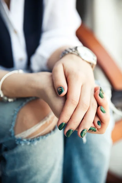 Chica elegante sentado en pantalones vaqueros rotos y moderno esmalte de uñas verde , —  Fotos de Stock