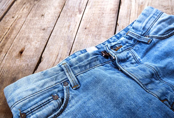 Jeans auf einem hölzernen Hintergrund. der obere Teil. Kleidung, Mode, — Stockfoto