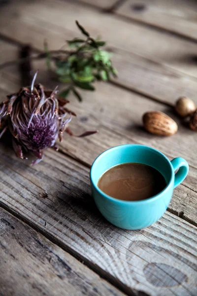 Una taza de café sobre fondo de madera, con flores y frutos secos. Gitanos —  Fotos de Stock