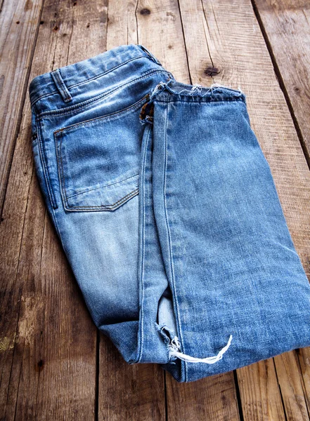 Stylish jeans folded on a wooden background. Clothing, fashion, lifestyle. — Stock Photo, Image