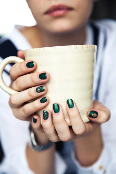 Stilvolles modisches Mädchen mit einer Tasse Kaffee und einer grünen Maniküre in Jeans. Mode, Pflege, Schönheit — Stockfoto