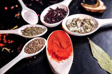 siyah bir zemin üzerine tahta kaşık baharat. Gıda