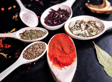 siyah bir zemin üzerine tahta kaşık baharat. Gıda