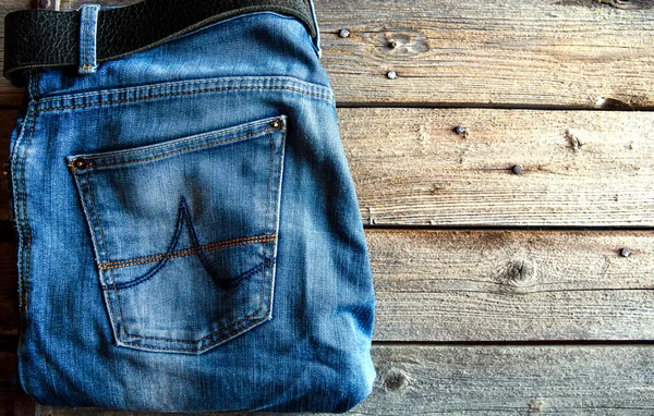 木製の背景をきちんと折られたジーンズ。衣料品、ファッション、ものもらい — ストック写真