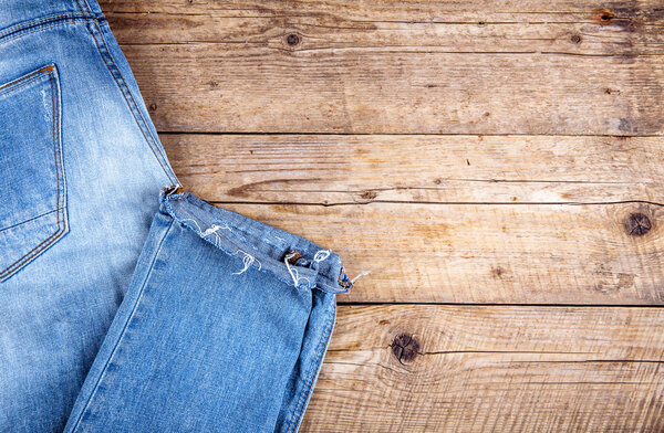 Stylish jeans folded on a wooden background. Clothing, fashion, lifestyle.