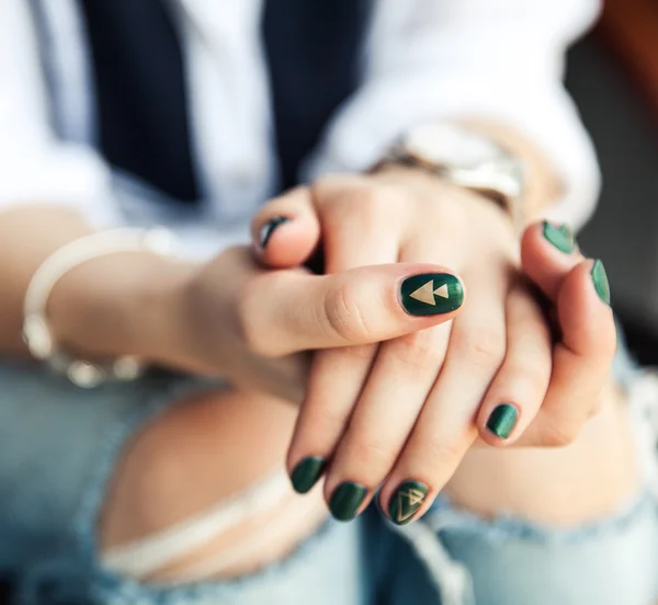 Stylish girl sitting in torn jeans and modern green nail Polish, watch, bracelet. Fashion, lifestyle, beauty, clothing. — Stock Photo, Image