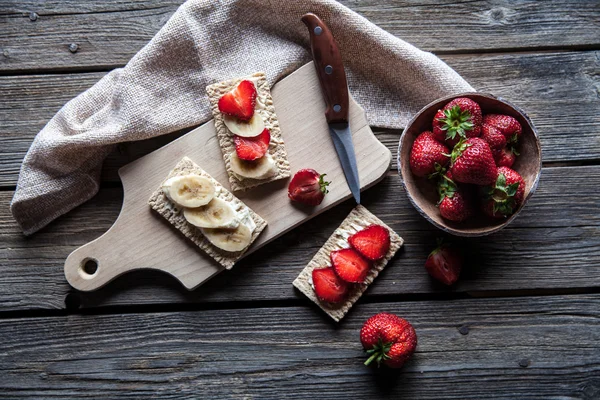 Fruktig toast på trä bakgrund. Jordgubbar, bröd, smör och ost. Vintage stil — Stockfoto