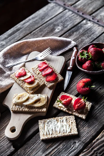 Fruktig toast på trä bakgrund. Jordgubbar, bröd, smör och ost. Vintage stil — Stockfoto