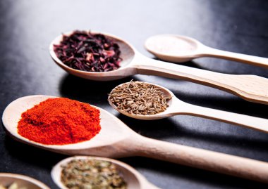 siyah bir zemin üzerine tahta kaşık baharat. Gıda