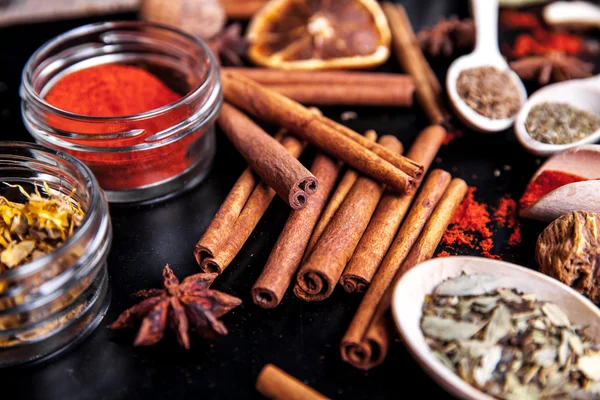 Wooden spoons with spices on black background — Stock Photo, Image