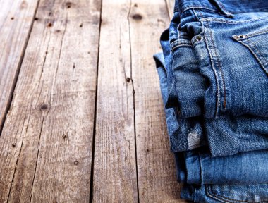 Ahşap arka planda üst üste dizilmiş kot pantolon