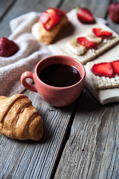 Heerlijk ontbijt met een kopje koffie en fruit broodjes, croissants. Aardbeien, chocolade, eten, drinken. — Stockfoto