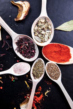 siyah bir zemin üzerine tahta kaşık baharat. Gıda