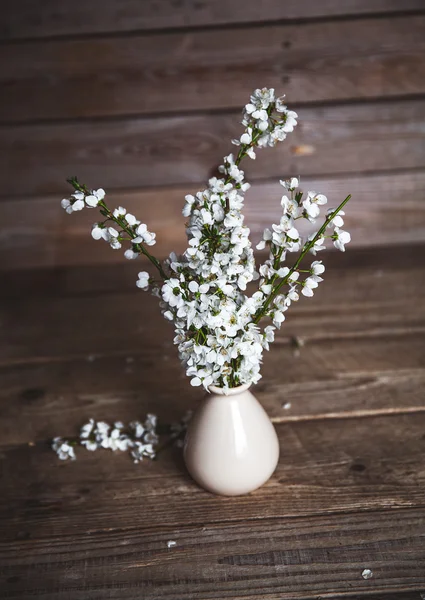 Vintage vase with cherry flowers on old wooden background. — Stock Photo, Image