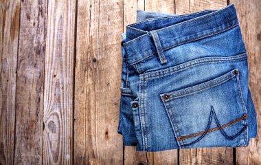 Ahşap arka planda üst üste dizilmiş kot pantolon