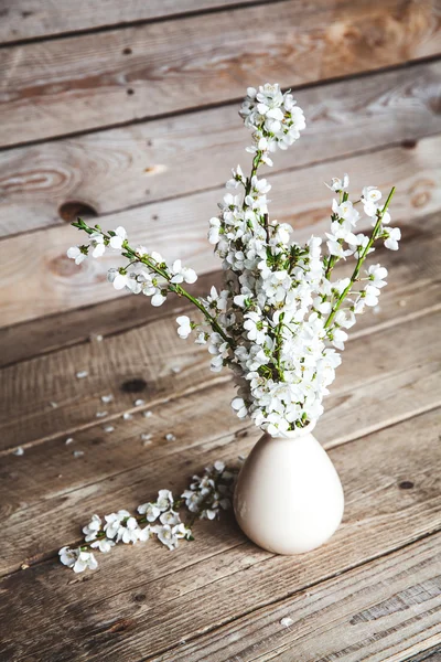 Vintage vase with cherry flowers on old wooden background. — Stock Photo, Image