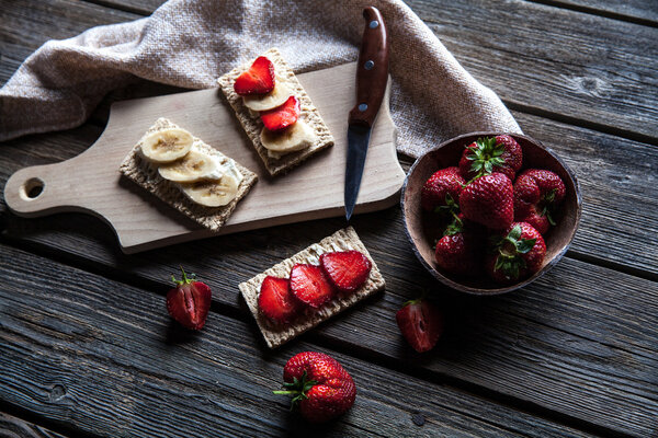 Fruity toast on wooden background. Strawberries, bread, butter and cheese.Vintage style