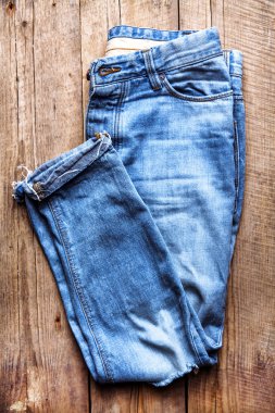 Şık kot bir ahşap arka plan üzerinde katlanmış. Giyim, moda, 