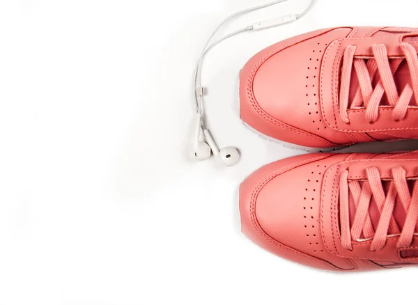 Zapatillas deportivas de color rosa sobre fondo blanco con auriculares. Entrenamiento. Deporte —  Fotos de Stock