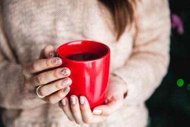 Kırmızı bir fincan kahve tutan kadının el. Güzel kış manikür ile. İçki, moda, sabah