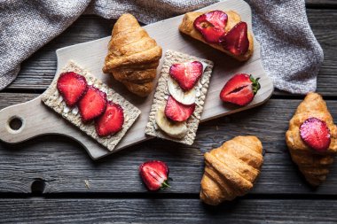 Çilek ve ekmek ahşap arka plan üzerinde leziz bir kahvaltı. Meyve, yemek, sandviç, peynir. Vintage tarzı.