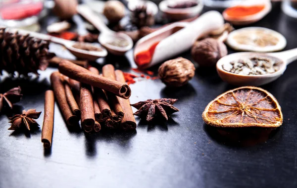 Wooden spoons with spices on black background — Stock Photo, Image