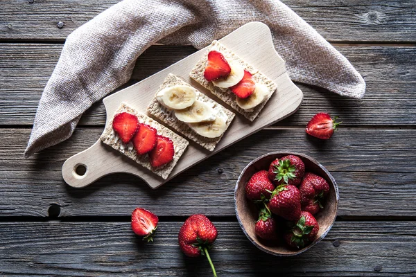 Fruktig toast på trä bakgrund. Jordgubbar, bröd, smör och ost. Vintage stil — Stockfoto