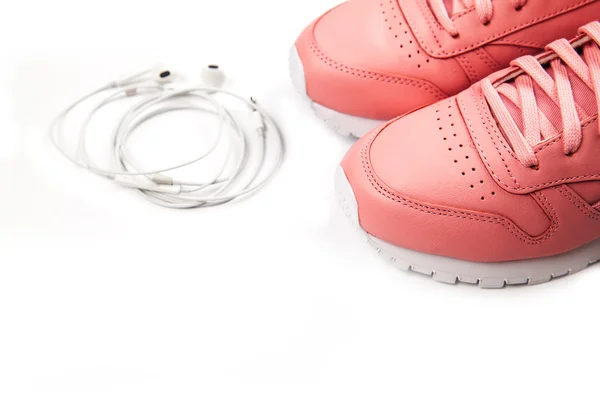 Zapatillas deportivas de color rosa sobre fondo blanco con auriculares. Entrenamiento. Deporte —  Fotos de Stock
