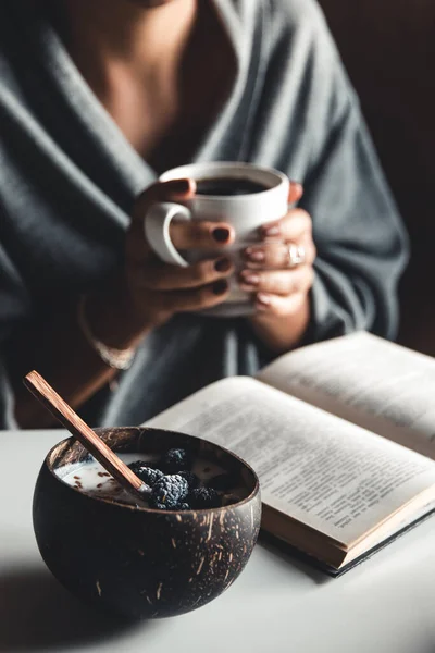 Zdravá snídaně, jogurt s fíky v kokosové misce. Pravý začátek dne. káva a kniha. — Stock fotografie